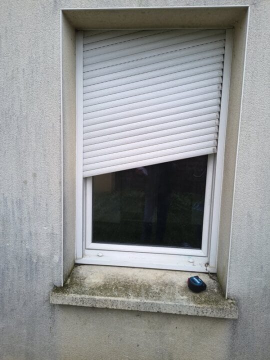 Volet roulant bloqué en biais sur façade — lames tordues, remplacement nécessaire à Caen