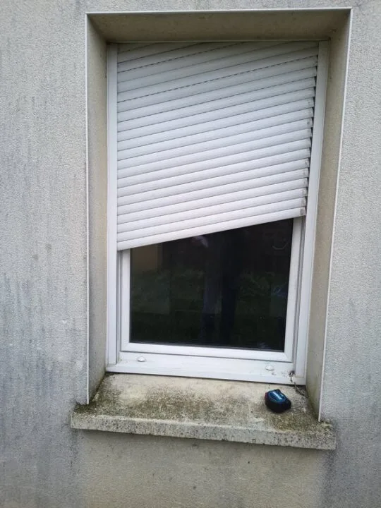 Volet roulant bloqué en biais sur façade — lames tordues, remplacement nécessaire à Caen